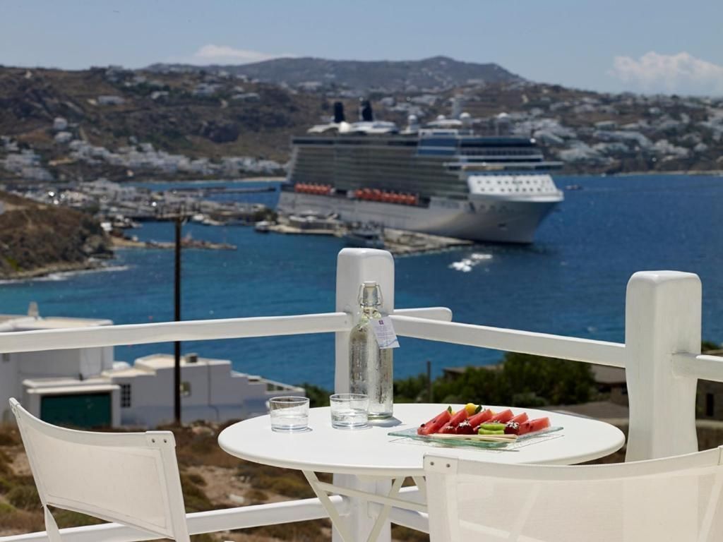 Weißer Tisch auf einer Terrasse mit Wassermelone und Meerblick auf ein Kreuzfahrtschiff.