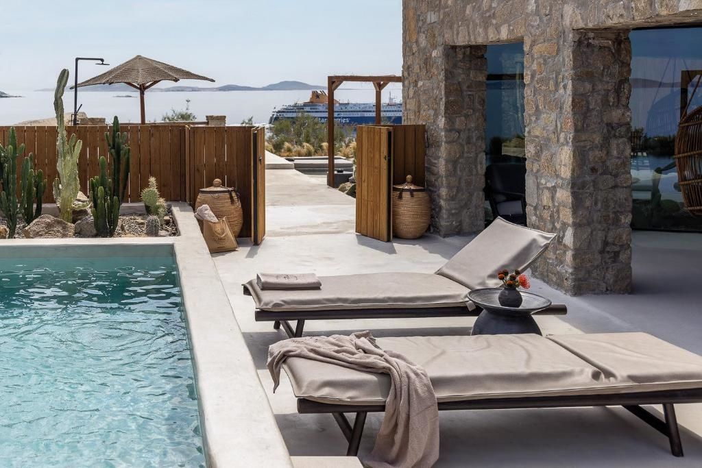 Sonnenliegen auf einer Terrasse am Pool mit Blick auf das Meer und ein Schiff.