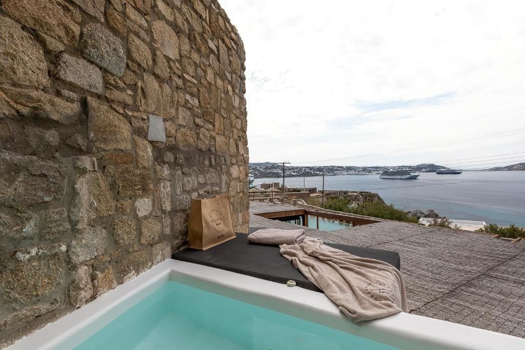 Ein kleines Tauchbecken auf einer Terrasse an einer Steinmauer mit Blick aufs Meer.