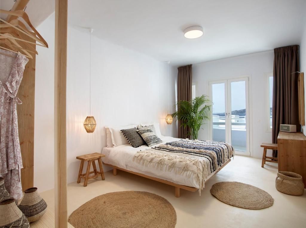 Helles Hotelzimmer mit Holzbett, gewebten Kissen, Rattanleuchten und runden Teppichen.