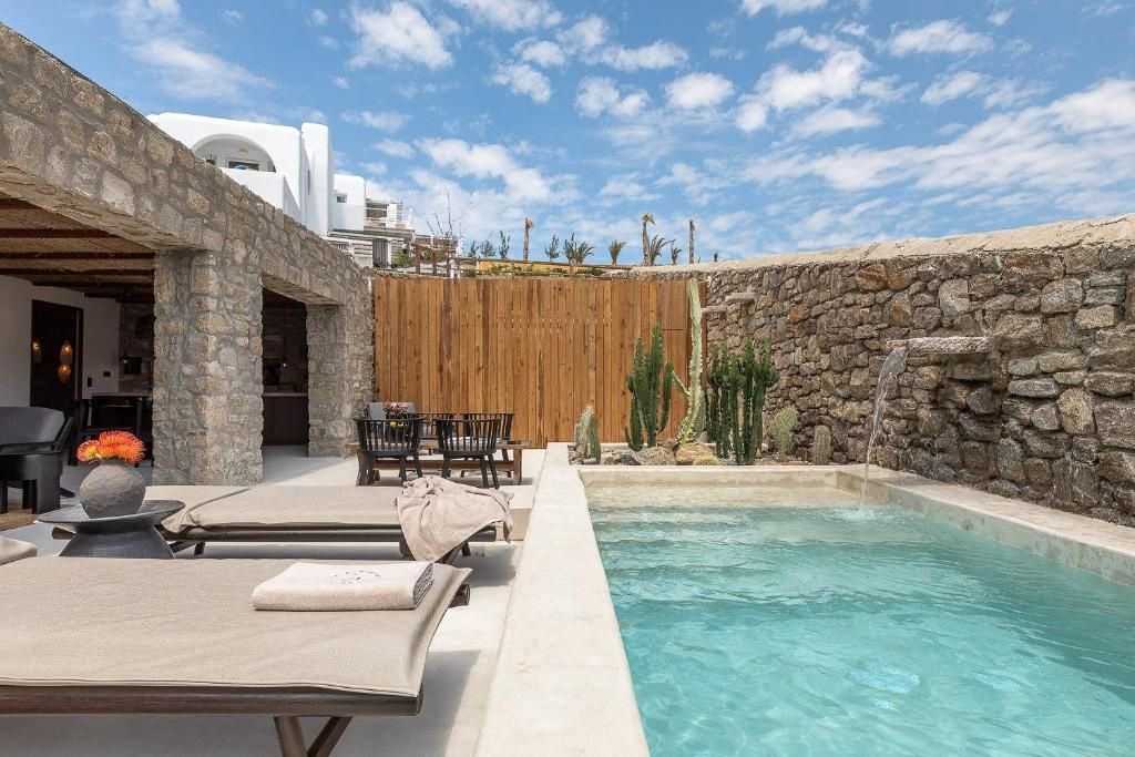 Terrasse mit Pool, kleine Wasserspiele an der Steinwand und Liegestühlen.