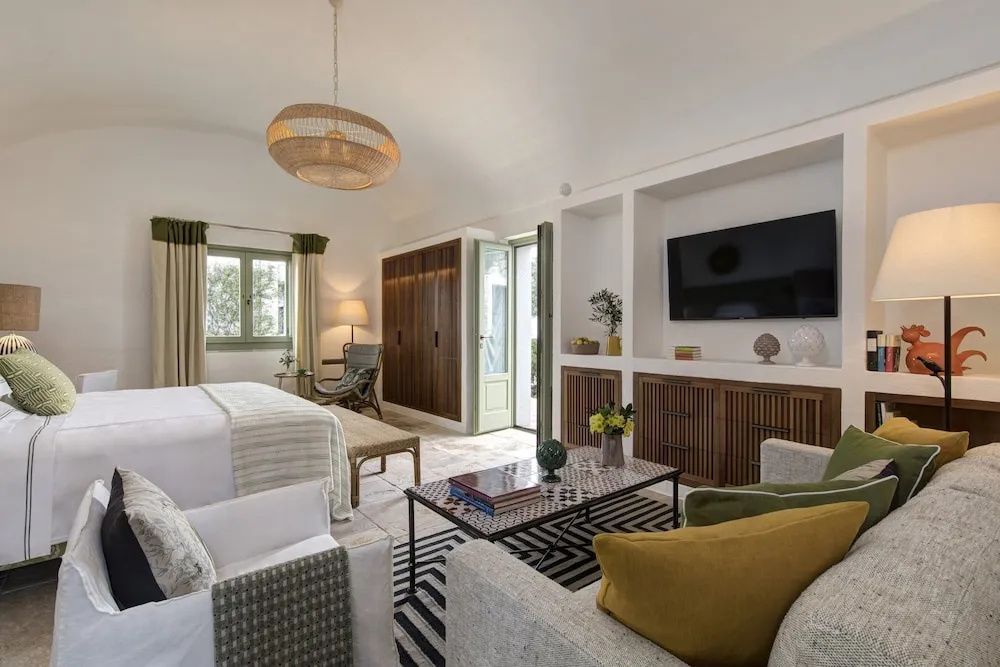 Helles Hotelzimmer mit Doppelbett, Sitzgruppe, Wandfernseher und Terrassentür.