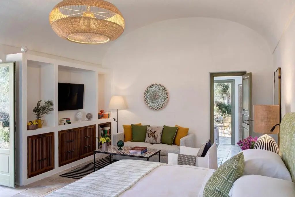 Wohnbereich einer Suite mit hellem Sofa, bunten Kissen und Fernsehnische.