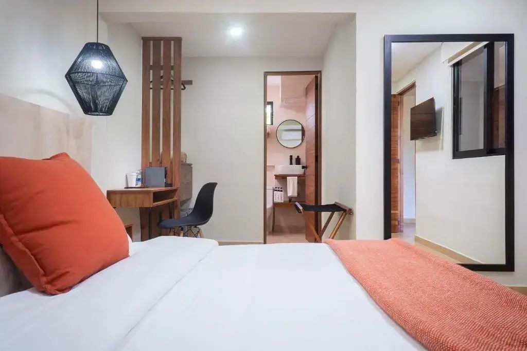 Moderner Schlafbereich mit Doppelbett, Schreibtisch und offenem Blick in das Badezimmer.