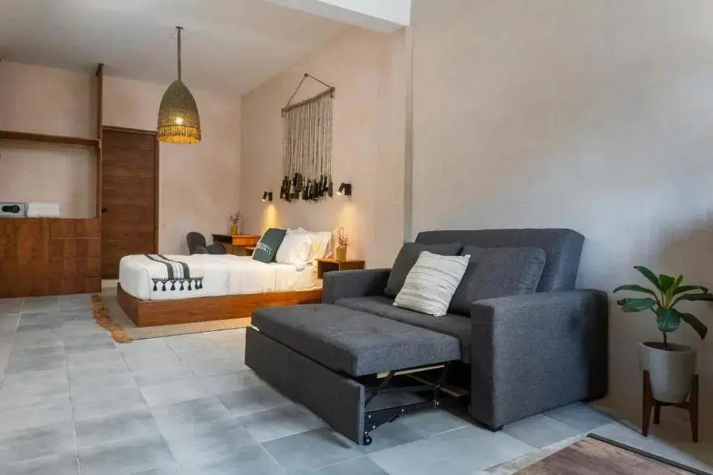 Ausgezogenes graues Schlafsofa im Vordergrund und Holzdoppelbett im Hintergrund.