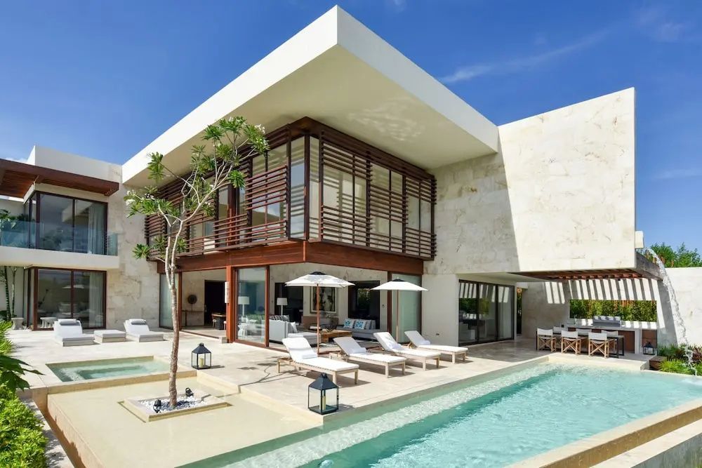 Moderne zweistöckige Villa mit Holzlamellen, Terrasse, Sonnenliegen und Swimmingpool.