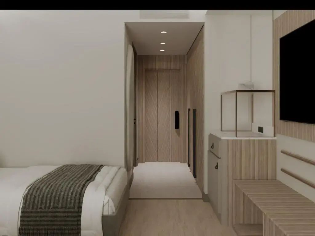 Eingangsbereich eines Hotelzimmers mit hellem Holz und sichtbarer Bettkante.