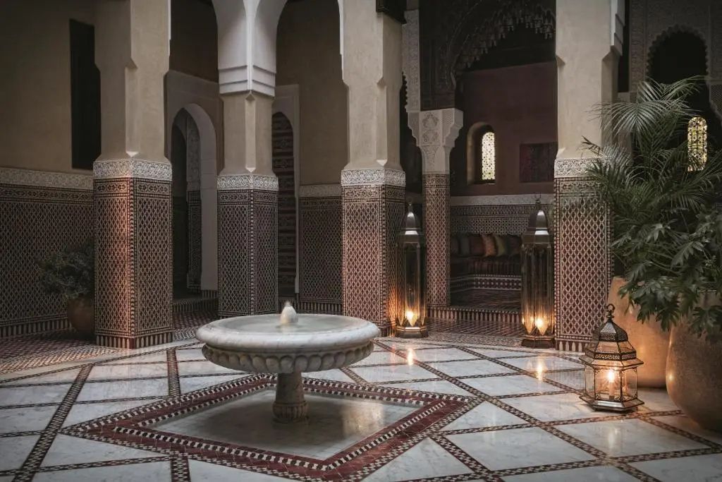Innenhof mit traditionellem Marmorbrunnen, Mosaikfliesen und verzierten Säulen.