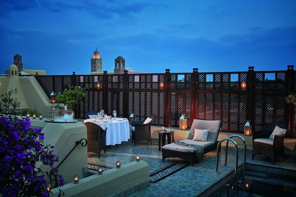 Dachterrasse mit gedecktem Esstisch, Liegestuhl und Blick auf ein Minarett in der Dämmerung.