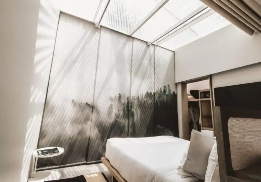 Hell erleuchtetes Hotelzimmer mit Doppelbett und bedruckter Wand.
