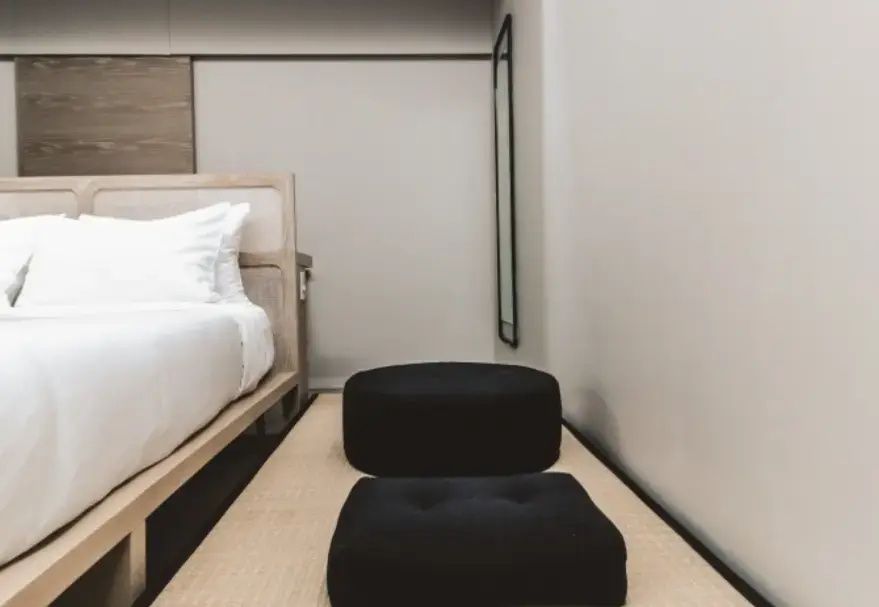 Zimmer im japanischen Stil mit zwei schwarzen Sitzkissen und Holzbett.