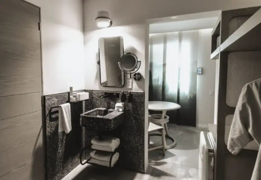 Waschtisch aus dunklem Stein mit Spiegel und Handtüchern im modernen Badezimmer.