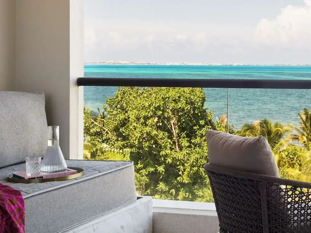 Sitzgelegenheit auf dem Balkon mit Blick über grüne Vegetation auf das Meer.