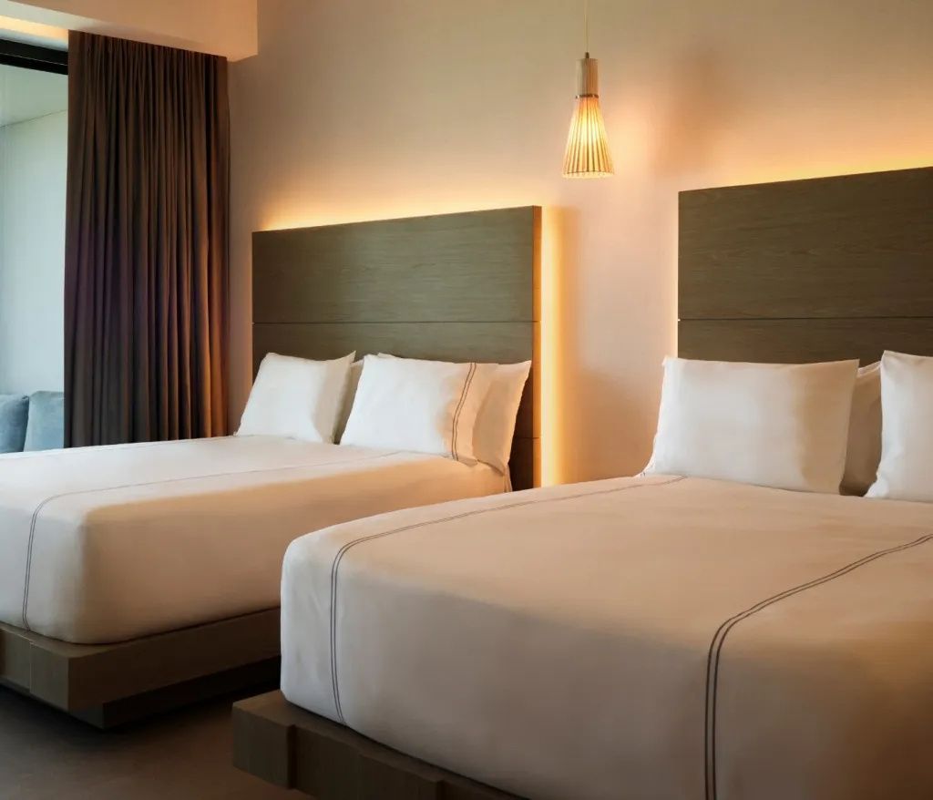 Zwei große Betten im Hotelzimmer mit beleuchteten Kopfteilen aus Holz.