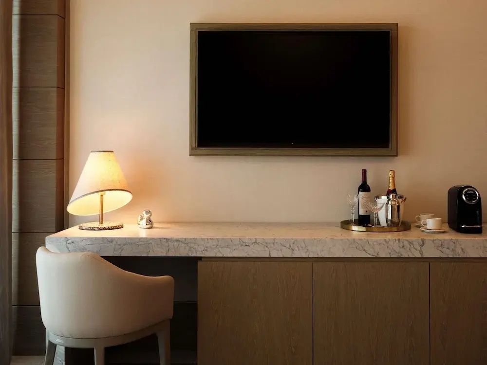 Schreibtisch aus Marmor mit Tischlampe, Stuhl und einem Fernseher an der Wand.