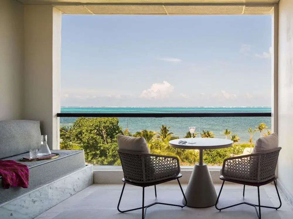 Möblierter Balkon mit zwei Stühlen, einem Tisch und Blick auf das türkisfarbene Meer.