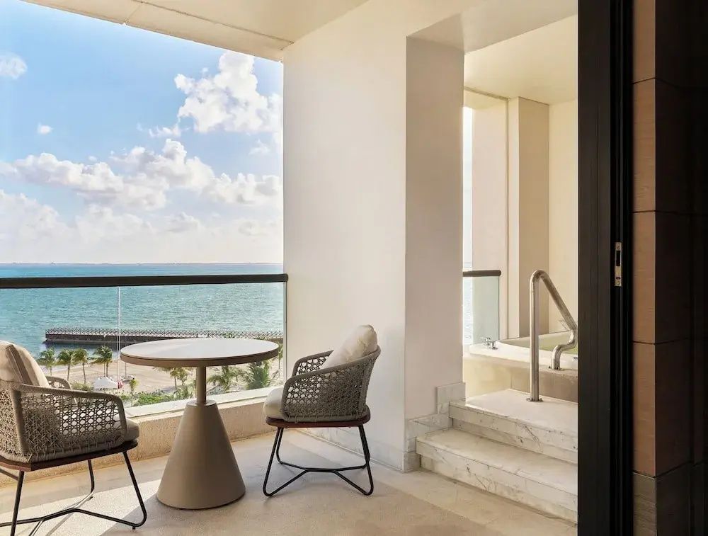 Überdachter Balkon mit Tisch, Stühlen und freiem Blick auf das türkise Meer.
