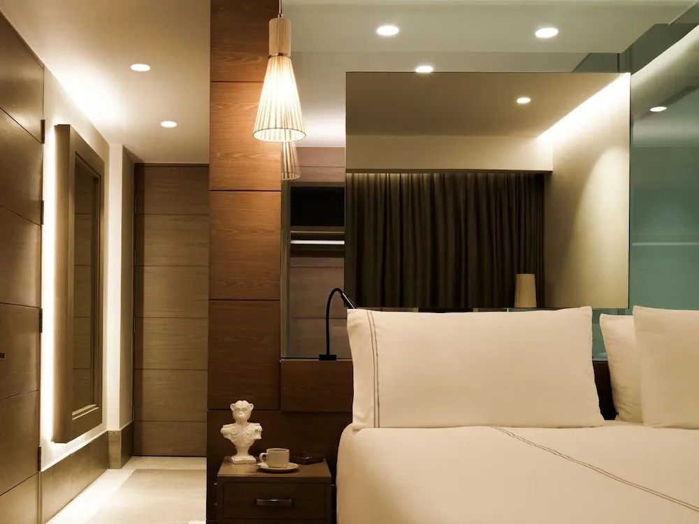 Modernes Hotelzimmer mit Bett, Holzverkleidung, Pendelleuchte und Nachttisch.