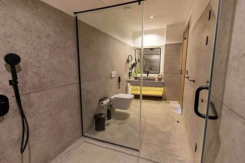 Badezimmer mit moderner Glasdusche, Wand WC und beleuchtetem Waschtisch.
