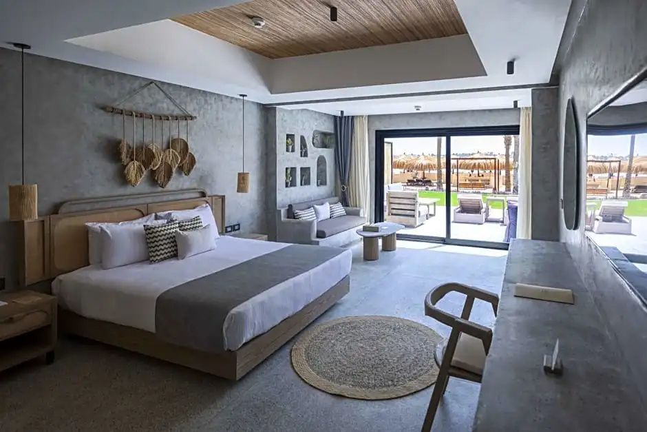 Helles Schlafzimmer mit großem Doppelbett, Sitzecke und Zugang zur Terrasse.