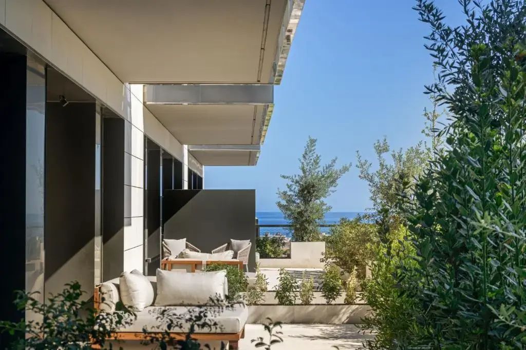 Terrasse mit Lounge-Möbeln, grünen Pflanzen und Blick auf das Meer.