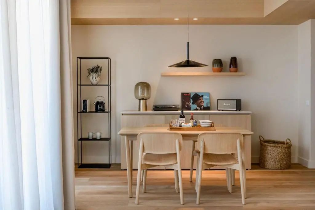 Esstisch aus Holz mit Stühlen, Sideboard und Regal in hellem Wohnbereich.