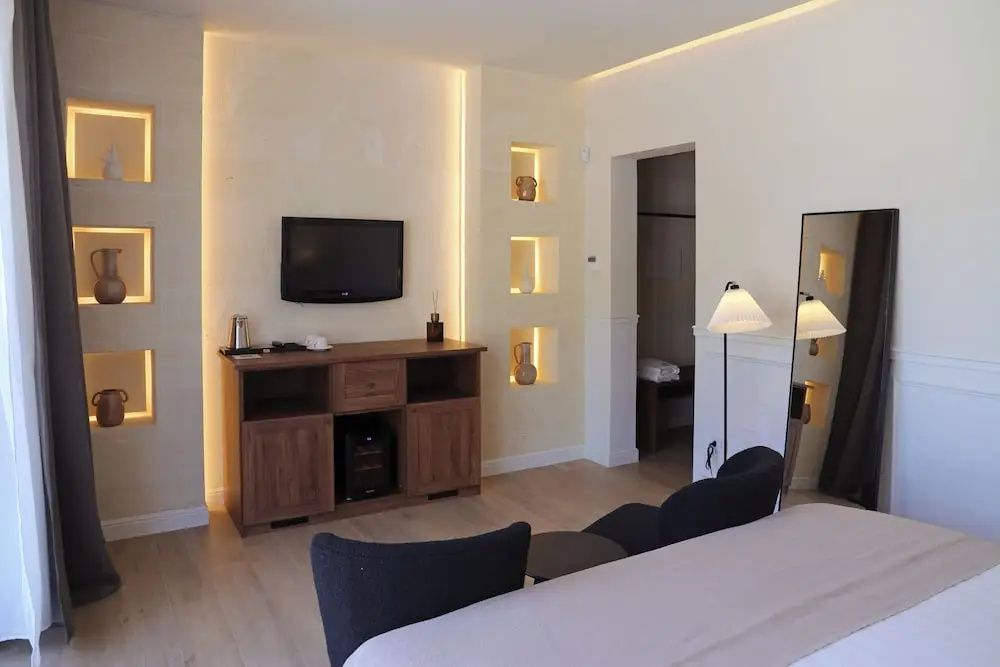 Fernseher auf Holzanrichte und beleuchtete Wandnischen im Hotelzimmer.