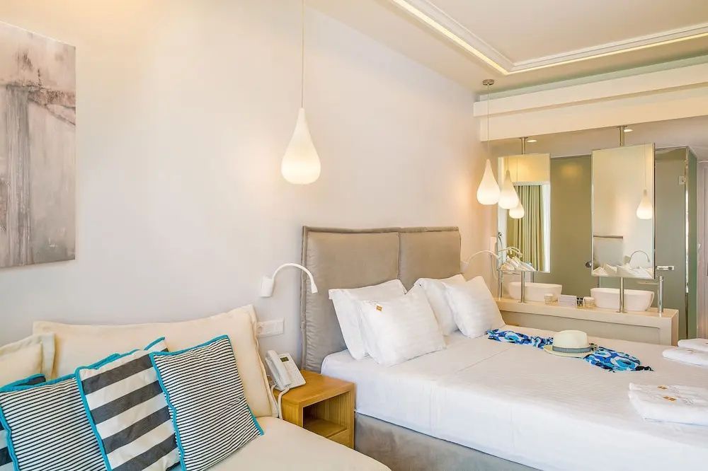 Helles Hotelzimmer mit großem Doppelbett, Kissen und hängenden Lampen.