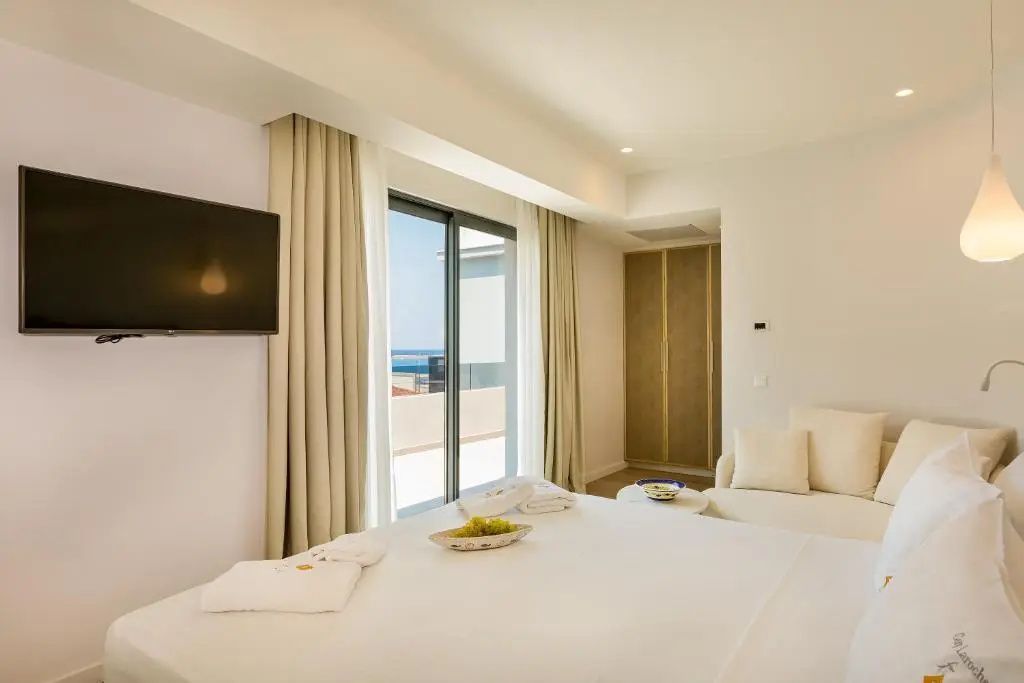 Helles Zimmer mit Doppelbett, Flachbild-TV und Schiebetür mit Ausblick auf das Meer.