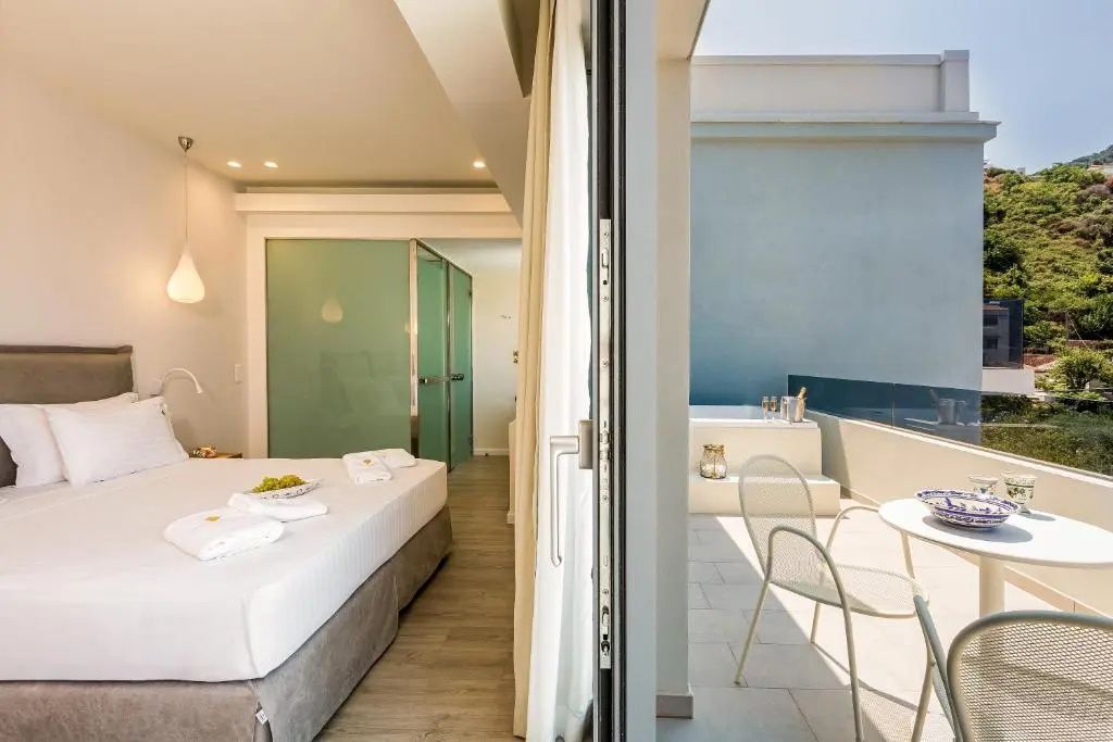 Helles Schlafzimmer mit Doppelbett und Blick auf die angrenzende Terrasse mit Whirlpool.