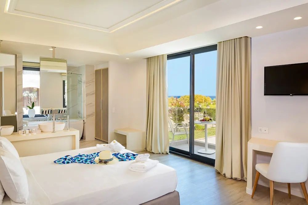 Helles Schlafzimmer mit Doppelbett und großem Fenster zur Terrasse.