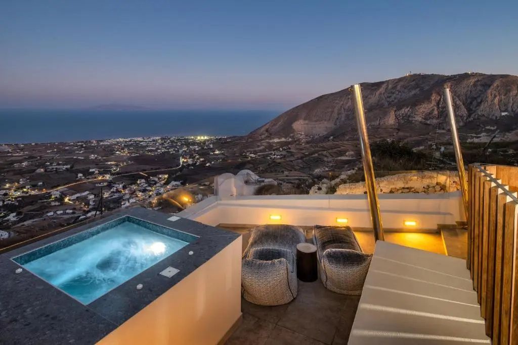 Beleuchtete Terrasse mit Jacuzzi und Weitblick auf die Küste in der Dämmerung.