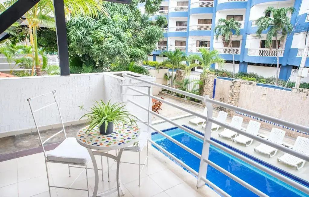 Balkon mit buntem Mosaiktisch und Blick hinunter auf einen blauen Swimmingpool.