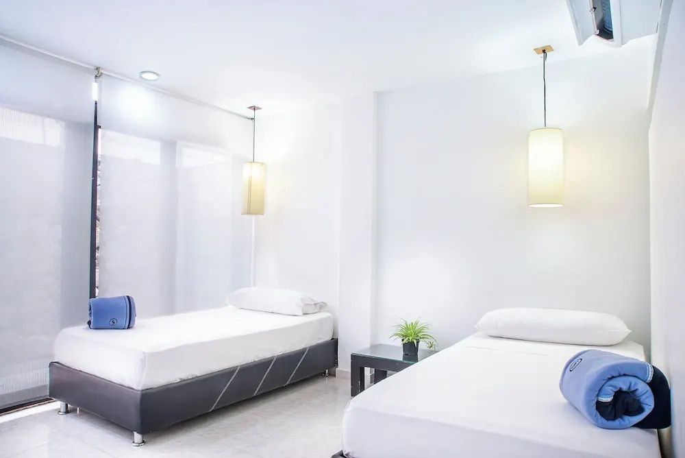 Hell eingerichtetes Schlafzimmer mit zwei Einzelbetten und modernen Hängelampen