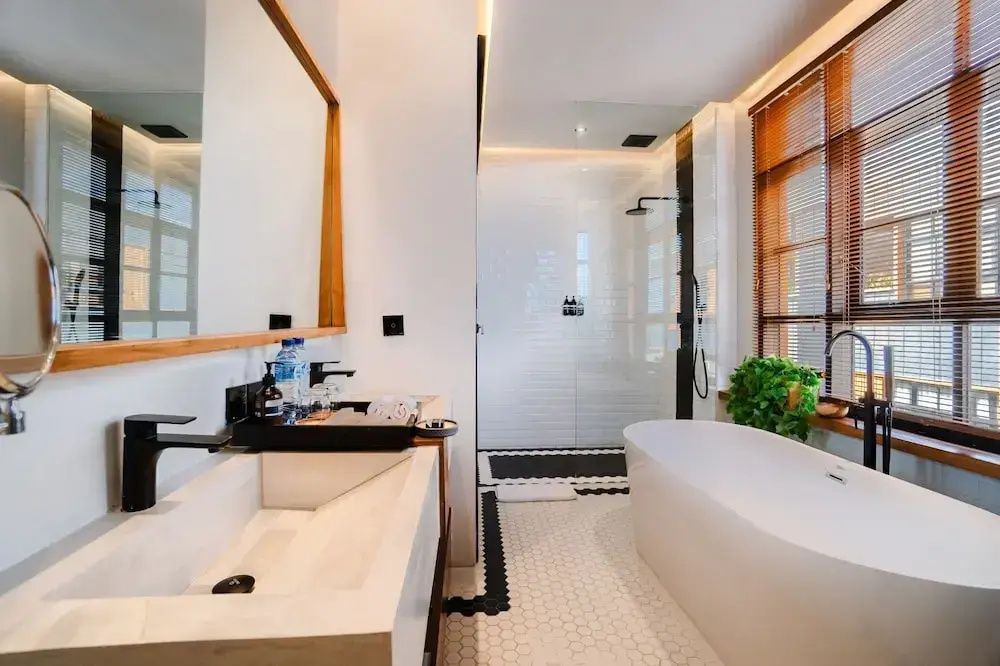 Badezimmer mit einer freistehenden Badewanne, ebenerdiger Dusche und hellem Waschtisch.