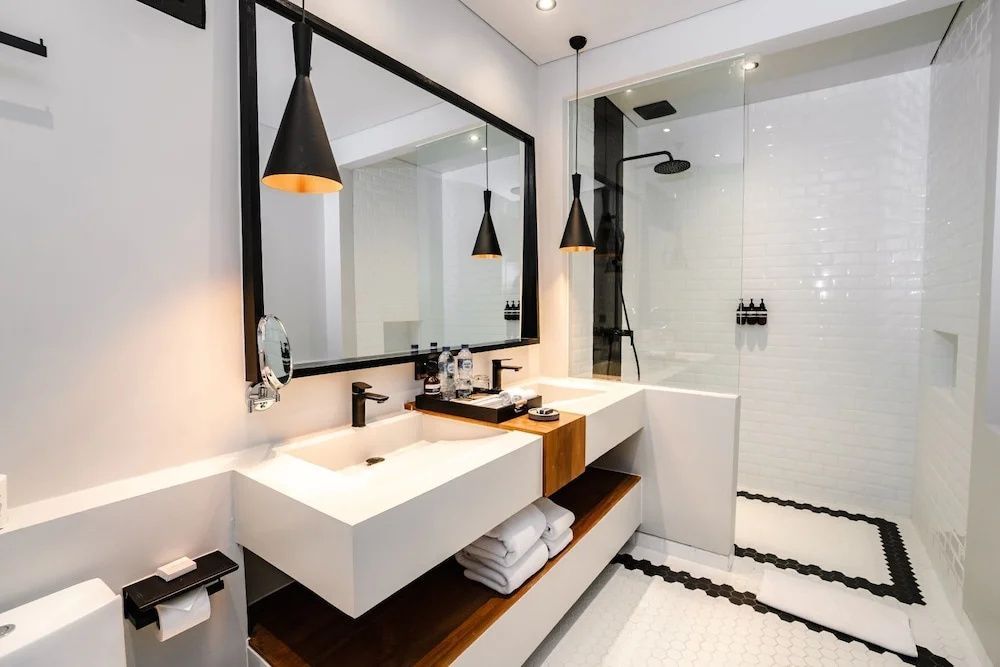 Badezimmer mit doppeltem Waschbecken, großem Spiegel und gläserner Duschkabine.