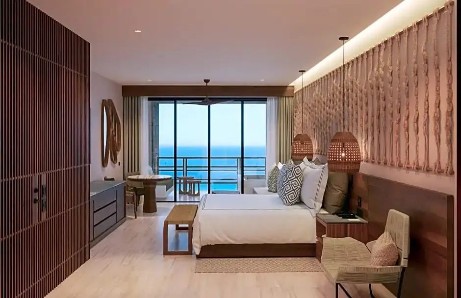 Helles Hotelzimmer mit großem Doppelbett und Balkon mit freiem Meerblick.