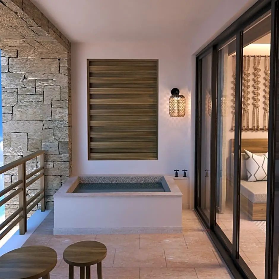 Balkon mit einem Whirlpool, Natursteinwand und Blick durch Schiebetüren ins Zimmer