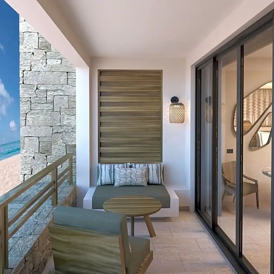 Balkon mit Sitzbank, Sessel, rundem Holztisch und Blick auf den Strand.