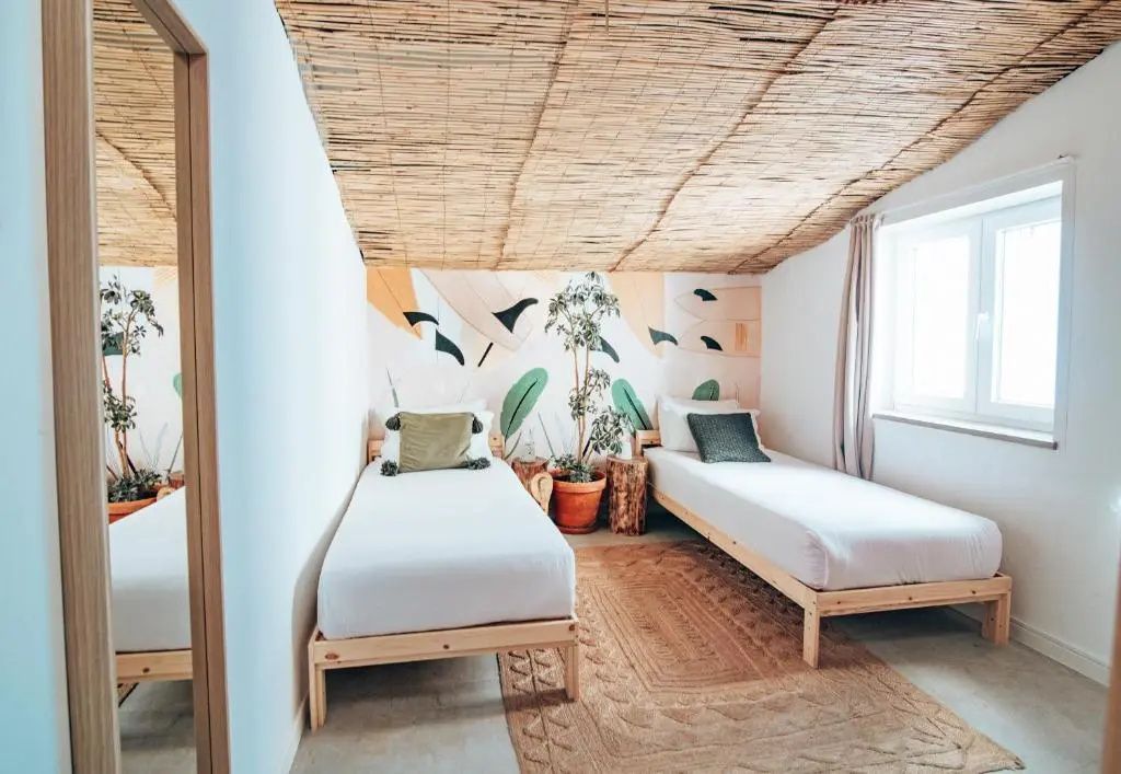 Zwei Einzelbetten aus Holz in einem Zimmer mit Schilfrohrdecke und Wandgestaltung