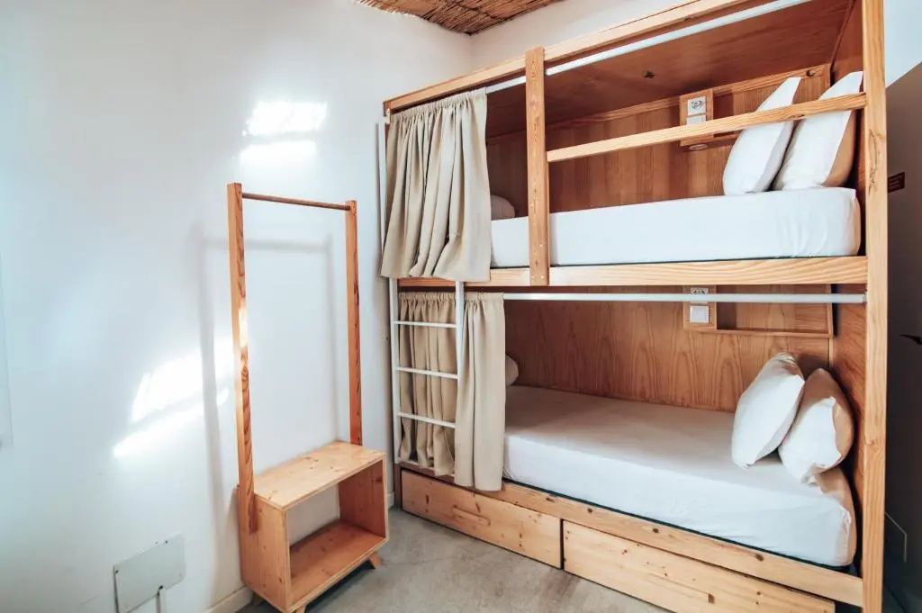 Hölzernes Etagenbett mit Stoffvorhängen und integrierten Holzfächern im Zimmer