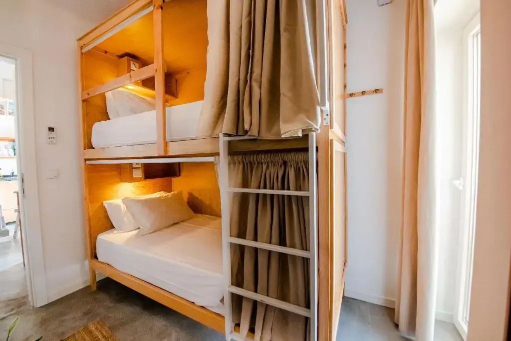 Mehrbettzimmer mit hölzernen Etagenbetten, die über Vorhänge für mehr Privatsphäre verfügen.