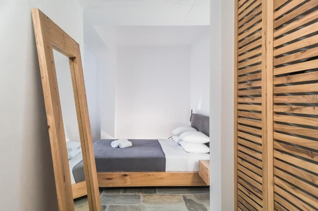 Schlafbereich im Hotelzimmer mit Doppelbett, Standspiegel und Steinboden.