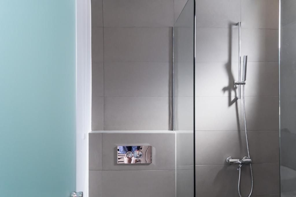 Modernes Badezimmer mit grau gefliestem Duschbereich und einer Abtrennung aus Glas.