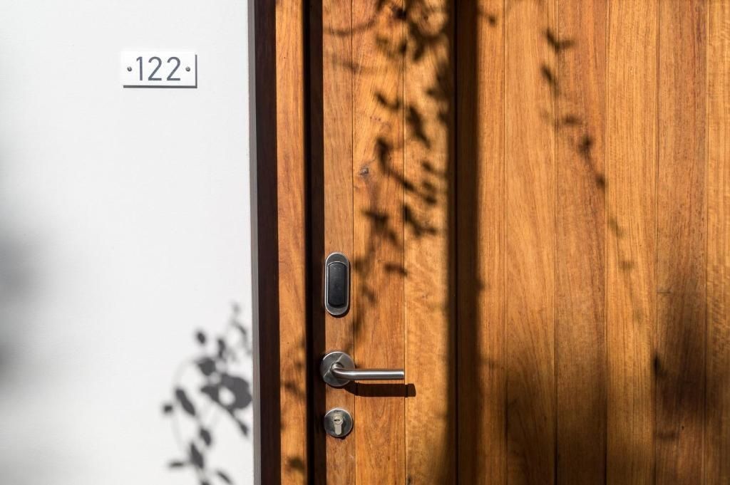 Nahaufnahme einer Holztür mit Türschloss und Schild der Zimmernummer 122.
