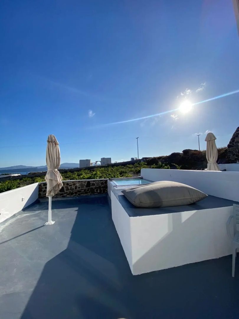 Sonnige Terrasse mit Sitzkissen, Sonnenschirmen und Blick auf die umliegende Landschaft.