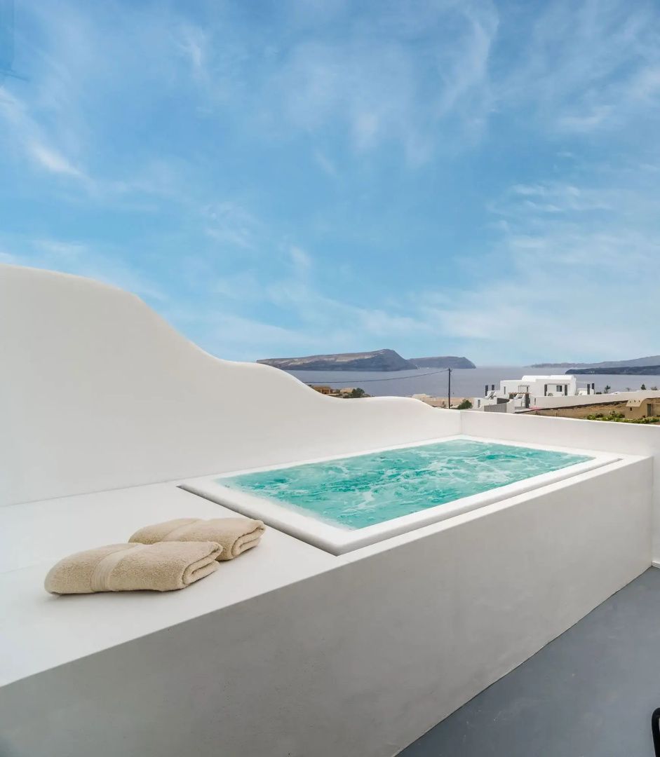 Whirlpool auf einer weißen Terrasse mit weitem Blick über das Meer und die Küste.