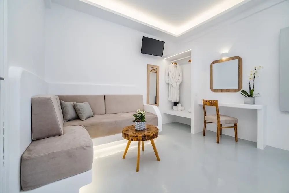 Sitzbereich im Hotelzimmer mit beigem Ecksofa, einem kleinen Holztisch und einem Schreibtisch.