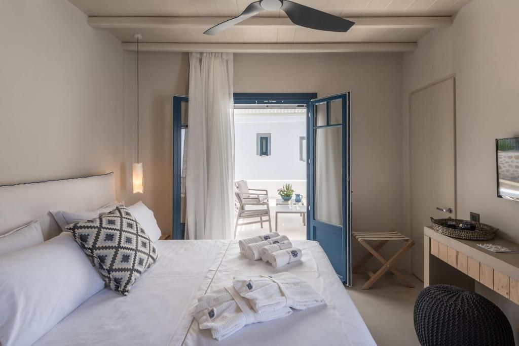 Schlafzimmer mit Doppelbett und geöffneten blauen Flügeltüren zur Terrasse.