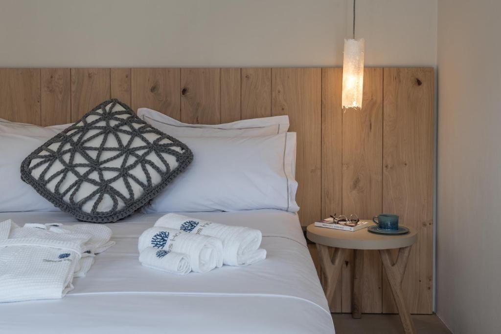 Doppelbett mit hölzernem Kopfteil, gefalteten Handtüchern und kleinem Beistelltisch